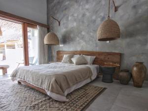 ein Schlafzimmer mit einem Bett und zwei Hängelampen in der Unterkunft Nagara Boutique Hotel in Jimbaran