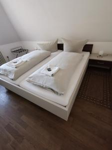 a large white bed with white sheets and pillows at City Hotel Franziska in Straubing