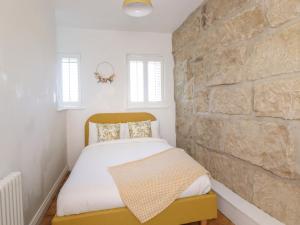 a bedroom with a bed with a stone wall at Penistone View in Keighley