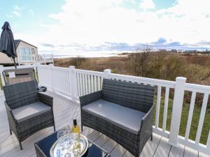 a deck with two chairs and a table with a glass of wine at Wansbeck View 2 in Ashington