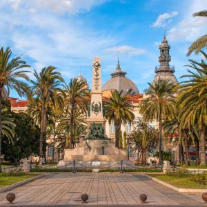 a monument in front of a building with palm trees at Carthago Suites (Centro - Casco histórico) in Cartagena