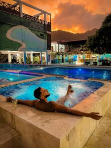 卡普兰干HOTEL BAHÍA PINORROA的日落时分，一名男子躺在游泳池里