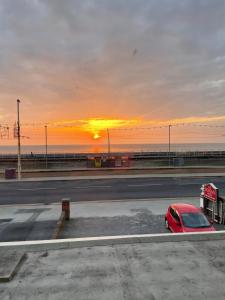 un coche rojo estacionado en un estacionamiento con la puesta de sol en The Roman Hotel, en Blackpool