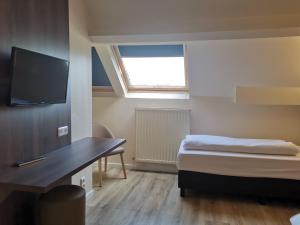 a room with a bed and a desk and a tv at Hotel Albert II Oostende in Ostend