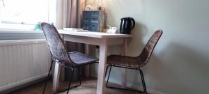 una mesa blanca con 2 sillas junto a una ventana en Overbosch, en Bilthoven