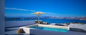 a swimming pool with an umbrella next to the water at CAPE 9 Villas & Suites in Akrotiri