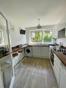 una cocina con armarios blancos, fregadero y ventanas en Dalriach Apartment, en Oban
