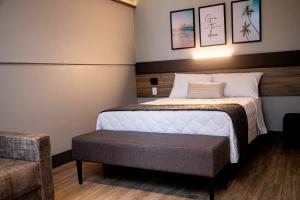 ein Hotelzimmer mit einem Bett mit einer Bank daneben in der Unterkunft Hotel Vila Catavento in Petrolina