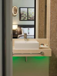 a bathroom with a sink in front of a bedroom at Holiday Inn London - Whitechapel, an IHG Hotel in London