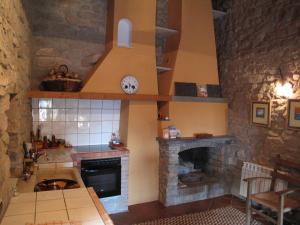 a kitchen with a stone fireplace and a sink at L'Esgolfa de ca l'Ortís in Figuerosa