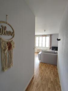 a living room with a couch and a sign on the wall at Gîte Le 101ème dans le centre de Ste Mère Église in Sainte-Mère-Église