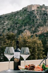 Una botella de vino y dos copas en una mesa. en Kastello Hotel en Nafplio