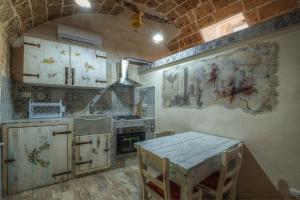 ナルドにあるLe casette di Nardòの白いキャビネットとテーブル付きのキッチンが備わります。