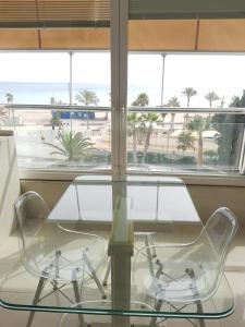 a glass table and two chairs in front of a window at 1 Linea Playa San Juan in Alicante
