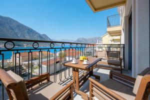 einen Balkon mit einem Tisch und Meerblick in der Unterkunft 2MONTENEGRO LIMETA APARTMENTS with pool in Kotor