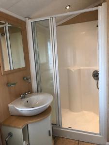 La salle de bains est pourvue d'un lavabo blanc et d'une douche. dans l'établissement Gold Caravan, à Harrietsfield