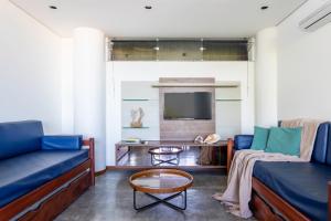 a living room with two blue couches and a tv at Casa com piscina, deck e vista para o mar in Morro de São Paulo