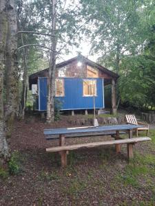uma pequena casa azul na floresta com um banco em Cabaña Don Humbert em Riñinahue