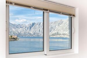 - une fenêtre avec vue sur le lac et les montagnes dans l'établissement Apartments Vuković, à Kotor