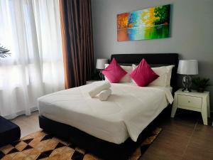 - une chambre avec un grand lit blanc et des oreillers roses dans l'établissement Izz'man Homestay Level 33 Troika Kota Bharu, à Kota Bharu