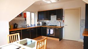 a kitchen with black cabinets and a table in it at The Lookout at Lauriston in Dartmouth