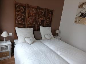 Un dormitorio con una cama blanca con dos corazones. en Les Fées Mer - Dieppe - Normandie en Dieppe