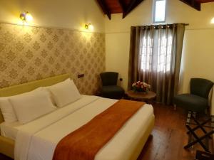 um quarto com uma cama, 2 cadeiras e uma janela em Lakeside Cottages em Nuwara Eliya
