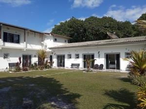 a white house with a yard at Pousada Camping e Pesca Bom Abrigo in Cananéia