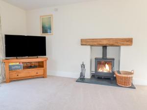 uma sala de estar com lareira e uma televisão de ecrã plano em Ilgram em Newquay