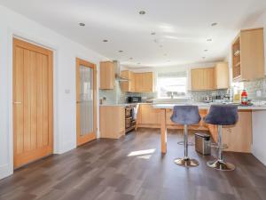 a kitchen with wooden cabinets and two bar stools at Ilgram in Newquay