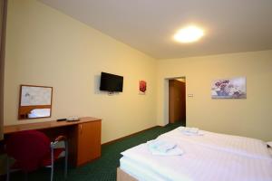 Hotel KRYŠTOF في بروستريدني بيتشفا: غرفة فندقية فيها سرير ومكتب وتلفزيون