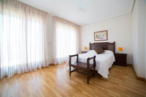 Schlafzimmer mit einem Bett, einem Stuhl und Fenstern in der Unterkunft Apartamentos Ría de Bayona in Baiona