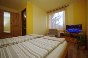 sypialnia z 2 łóżkami, telewizorem i krzesłem w obiekcie Bodza apartman w mieście Gyula