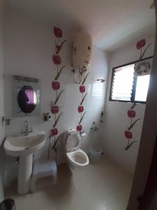 a bathroom with a sink and a toilet and flowers on the wall at kurinji residency in Ooty +4 photos