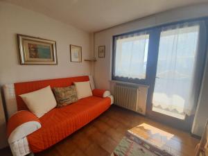 sala de estar con sofá naranja y ventana grande en Apartment San Giacomo - Brentonico, en Brentonico