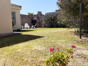 ein Hof mit einem Haus und ein paar rosa Blumen in der Unterkunft Sierras de La Punta in La Punta