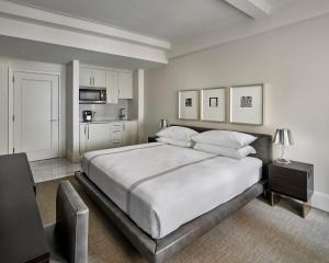 a white bedroom with a large bed and a kitchen at AKA Central Park in New York