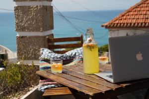 a table with a laptop and a bottle of orange juice and glasses at Chill in Ericeira Surf House in Ericeira
