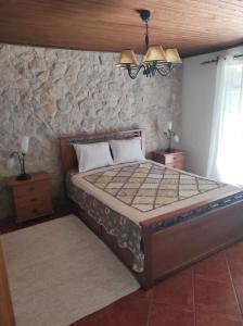 a bedroom with a bed and a stone wall at Fazenda do Marante in Tomar