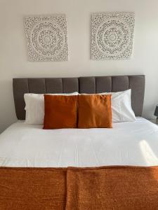 a bed with orange and white pillows in a bedroom at STOP at Pendarvis, Stone throw from beach! in Port Talbot