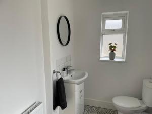 Baño blanco con lavabo y espejo en STOP at Pendarvis, Stone throw from beach!, en Port Talbot