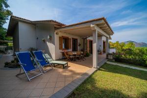 un patio con sedie blu e una casa di Villa Soledad - Rosa dei Venti a Capoliveri