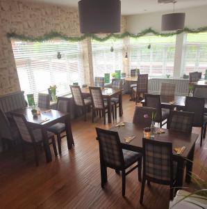 um restaurante com mesas e cadeiras de madeira e janelas em The Glazebury bar and restaurant with accommodation em Glazebury
