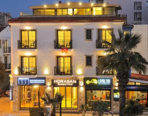 um grande edifício branco com janelas e uma palmeira em Horasan Boutique Hotel em Cesme