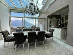 a dining room with a table and chairs and a large window at Brissago: Villa Claudia in Brissago