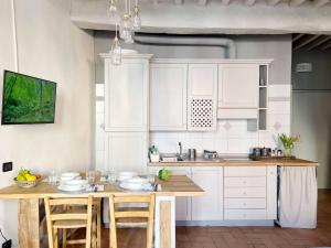 una cucina con armadi bianchi e tavolo in legno di Lovely nest in Parma centro a Parma