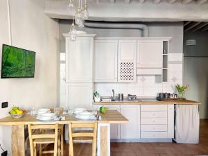 a kitchen with white cabinets and a wooden table at Lovely nest in Parma centro in Parma