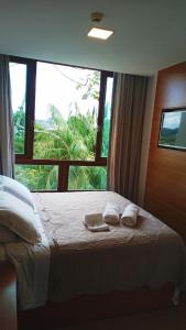 a bedroom with a bed with two towels and a window at Flat Pedra Azul - hospedagem nas montanhas in Pedra Azul