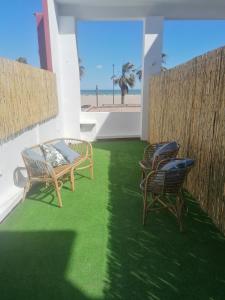 duas cadeiras e um banco num pátio com praia em Bet&CoBeach Apartments em Valência