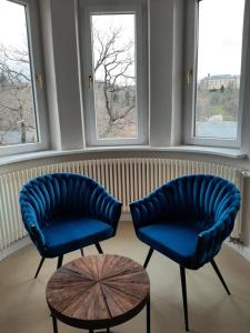 two blue chairs and a table in a room with windows at Hotel Villa Viktoria Luise in Blankenburg